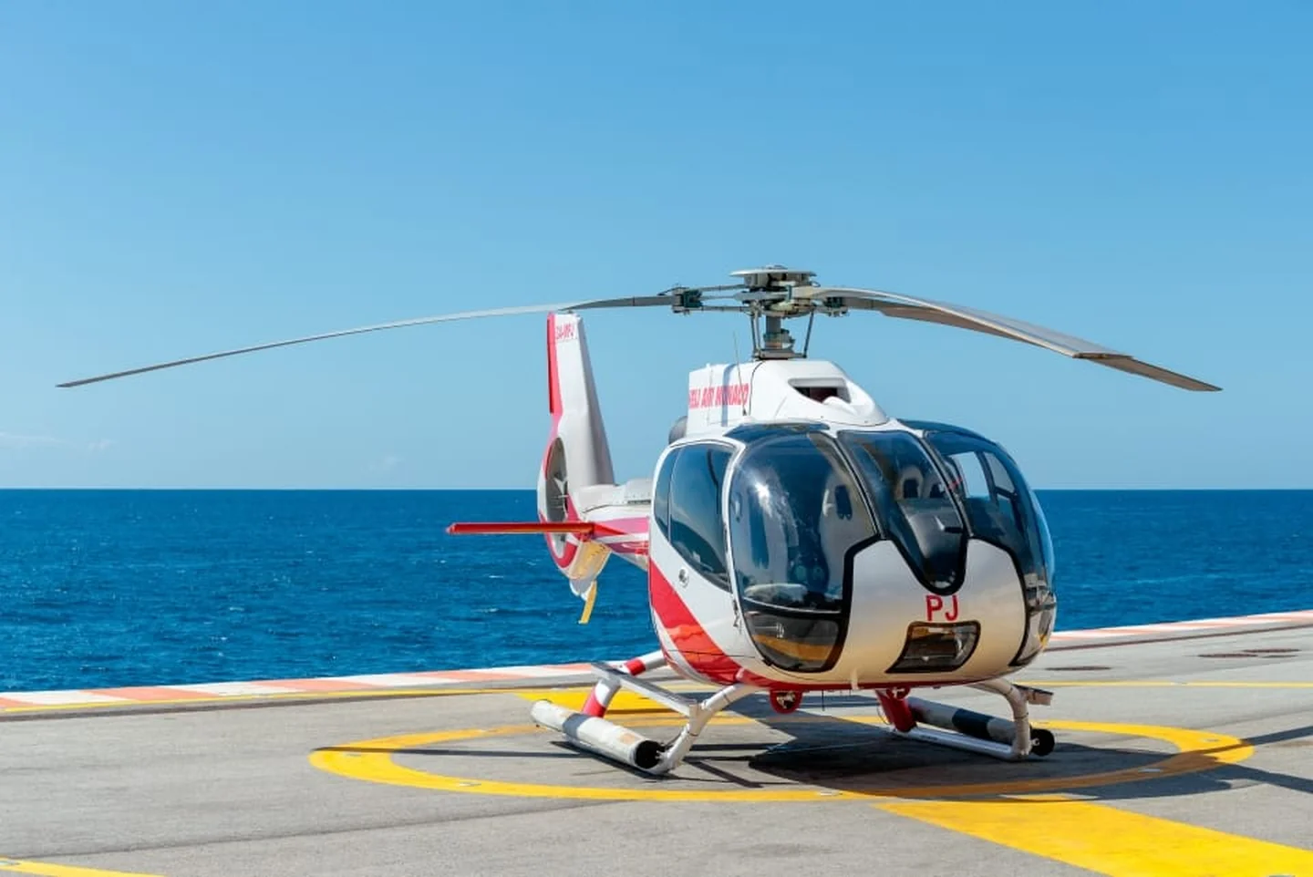Elicottero bianco e rosso sulla piazzola di atterraggio sul mare